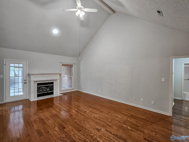 unfurnished living room featuring a fireplace, beamed ceiling, a textured ceiling, ceiling fan, and hardwood / wood-style floors