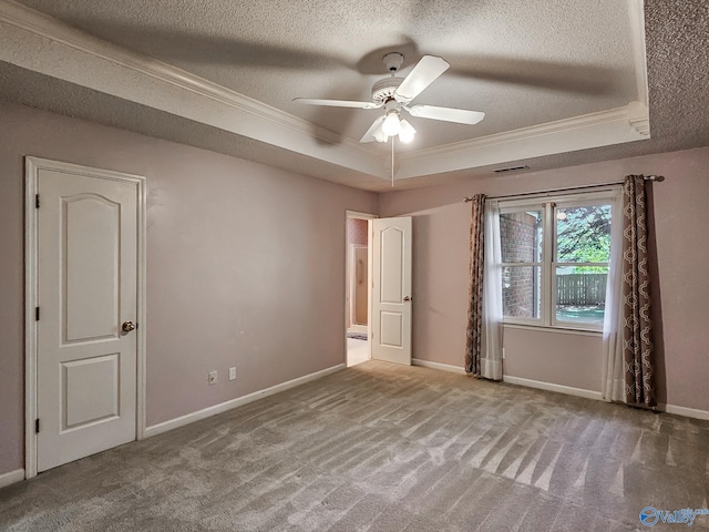 carpeted spare room featuring ceiling fan, a textured ceiling, a raised ceiling, and ornamental molding