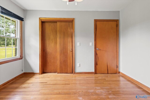 unfurnished bedroom with multiple windows, light wood-type flooring, and ceiling fan