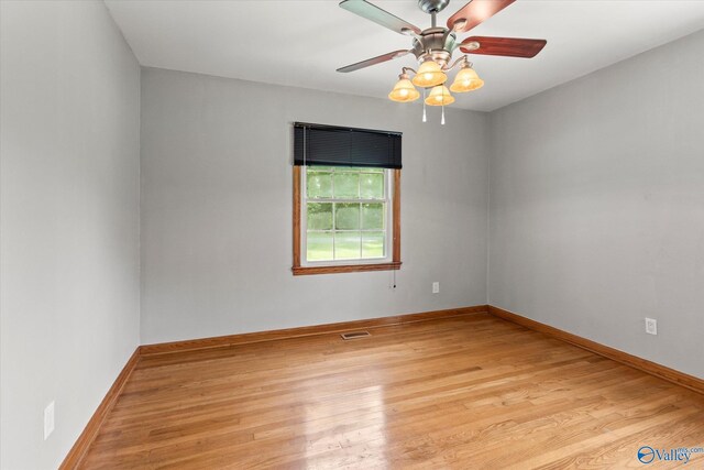 unfurnished room with light hardwood / wood-style flooring, wooden walls, and ceiling fan