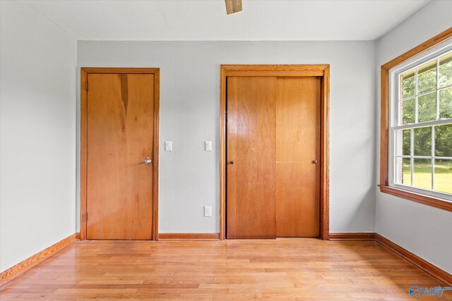 empty room featuring wood walls, light wood-type flooring, and ceiling fan