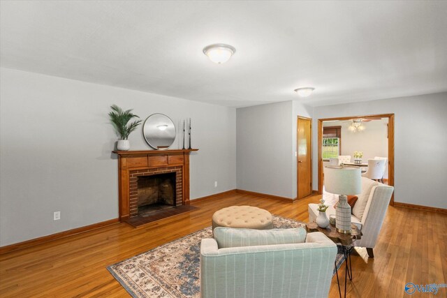 living room featuring a brick fireplace and light wood-type flooring