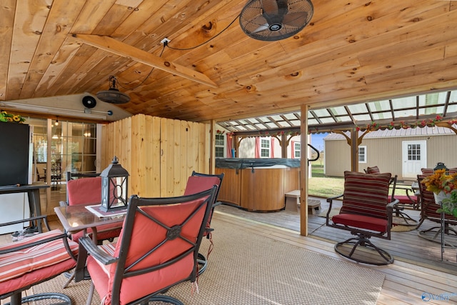 interior space with ceiling fan, light hardwood / wood-style flooring, wooden ceiling, vaulted ceiling with beams, and wood walls