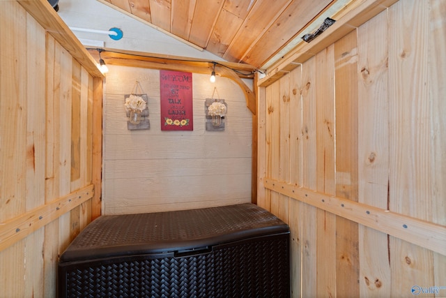 mudroom with wood ceiling, wooden walls, and vaulted ceiling