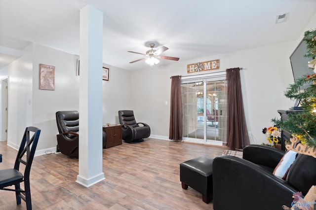 living room featuring ceiling fan, light wood-type flooring, and ornate columns