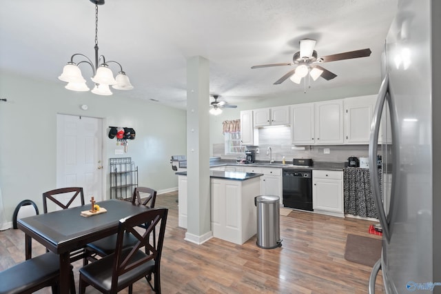 kitchen featuring hardwood / wood-style floors, white cabinets, stainless steel fridge, black dishwasher, and decorative light fixtures