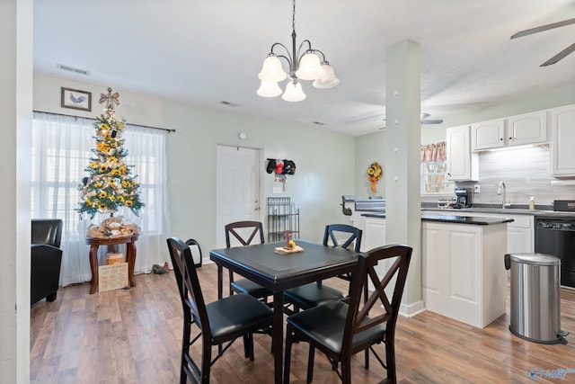 dining area with ceiling fan with notable chandelier, light hardwood / wood-style floors, and sink