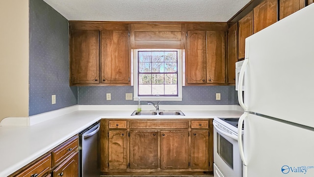 kitchen featuring brown cabinets, light countertops, a sink, white appliances, and wallpapered walls