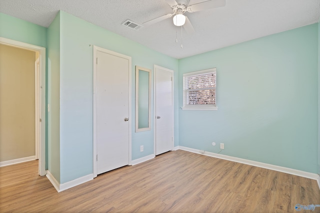 unfurnished bedroom with wood finished floors, visible vents, baseboards, and ceiling fan