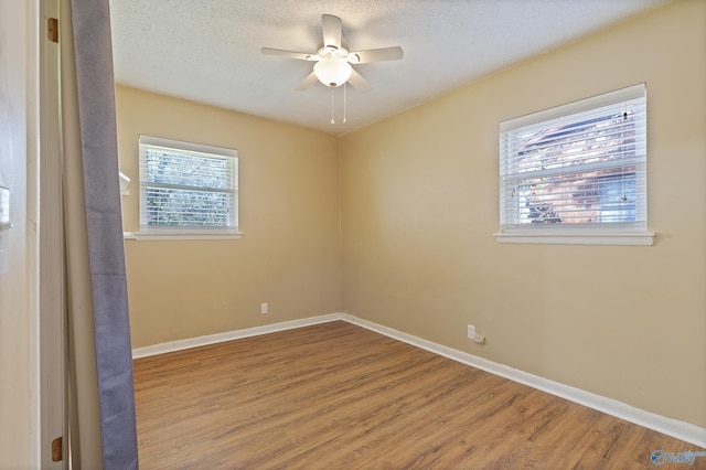 unfurnished room featuring baseboards, wood finished floors, a textured ceiling, and ceiling fan