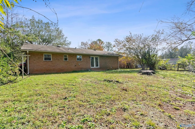 rear view of property featuring fence, brick siding, and a yard