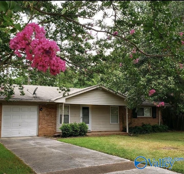 single story home with brick siding, a front lawn, driveway, and a garage