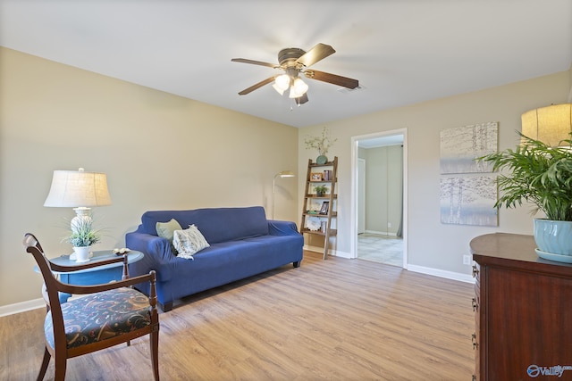 living area featuring baseboards, a ceiling fan, visible vents, and light wood finished floors
