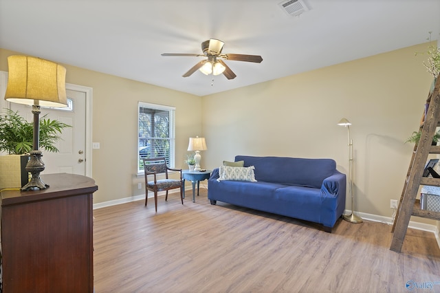 living area featuring light wood finished floors, baseboards, a ceiling fan, and visible vents