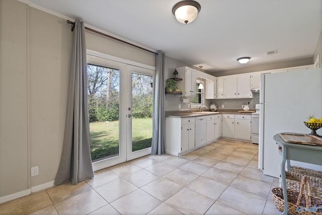 kitchen with white cabinets, visible vents, light tile patterned floors, a sink, and white appliances