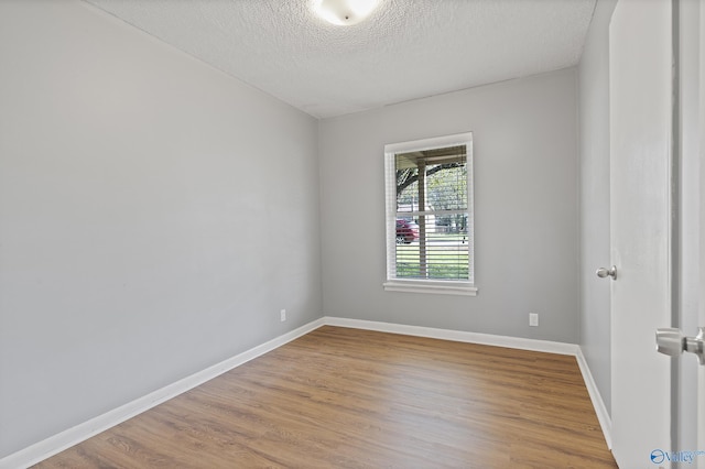 unfurnished room featuring baseboards, wood finished floors, and a textured ceiling