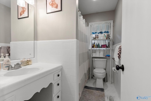 bathroom featuring toilet, tile walls, and vanity