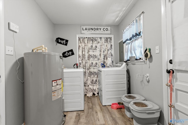 washroom with washing machine and dryer, electric water heater, and light hardwood / wood-style floors