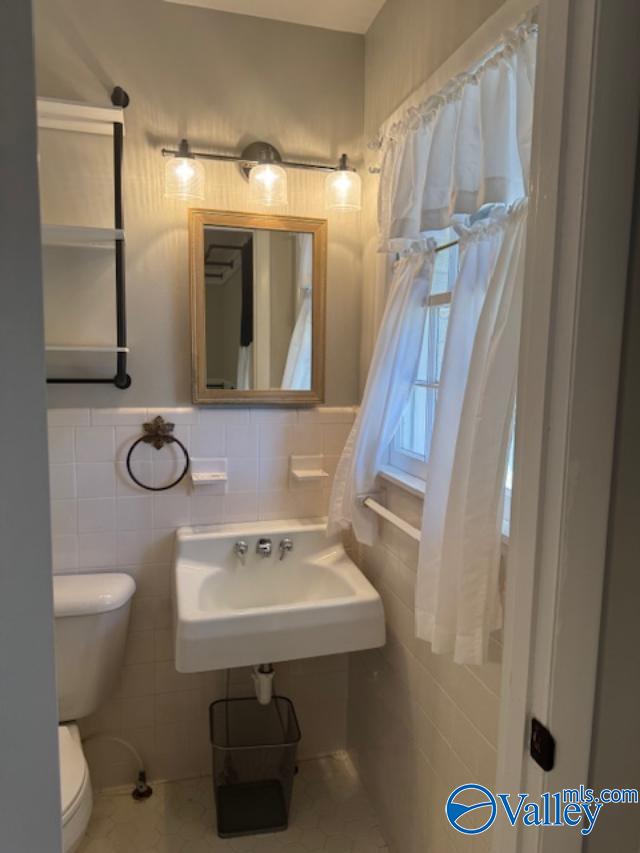 bathroom with tile patterned floors, sink, tile walls, and toilet