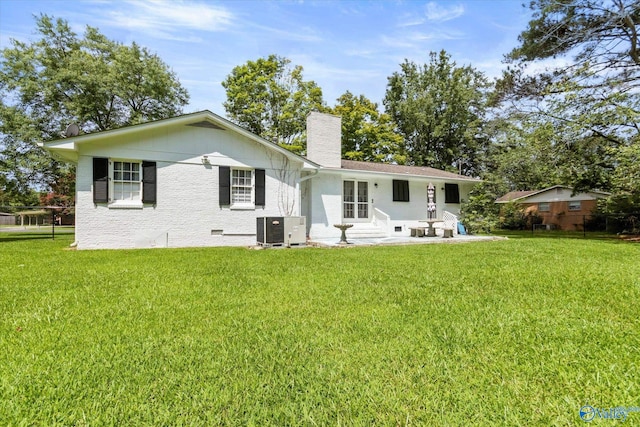 rear view of house with central AC unit and a lawn