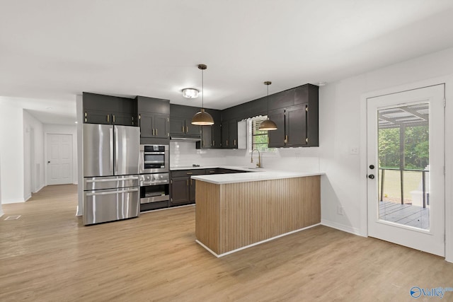 kitchen with light wood-style floors, light countertops, stainless steel appliances, baseboards, and a peninsula