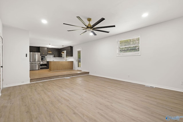 unfurnished living room with light wood finished floors, a ceiling fan, baseboards, recessed lighting, and visible vents