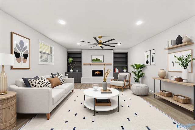 living area with a ceiling fan, recessed lighting, a large fireplace, and wood finished floors