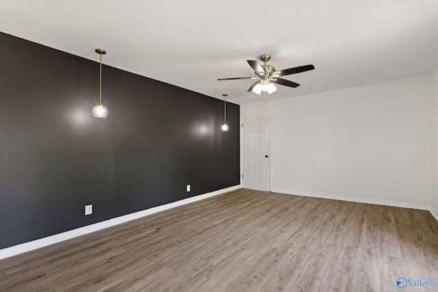 empty room featuring a ceiling fan, baseboards, and wood finished floors