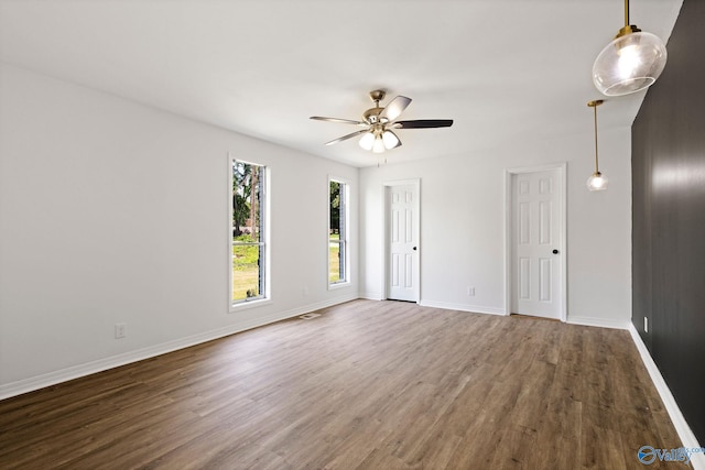 unfurnished room featuring baseboards, ceiling fan, wood finished floors, and visible vents