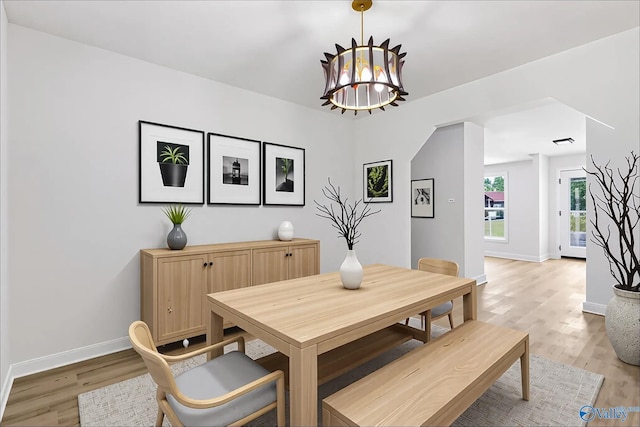 dining space featuring baseboards, light wood-style flooring, and a chandelier
