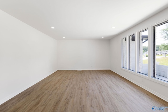 empty room with recessed lighting, baseboards, and wood finished floors