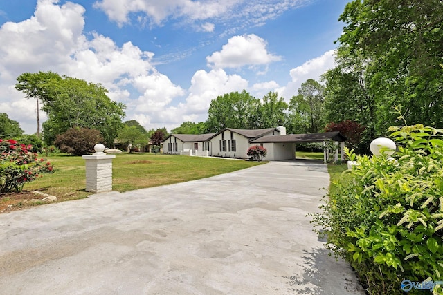 view of front of property featuring concrete driveway, a chimney, a front yard, and an attached carport