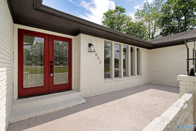 entrance to property with brick siding, french doors, and a patio