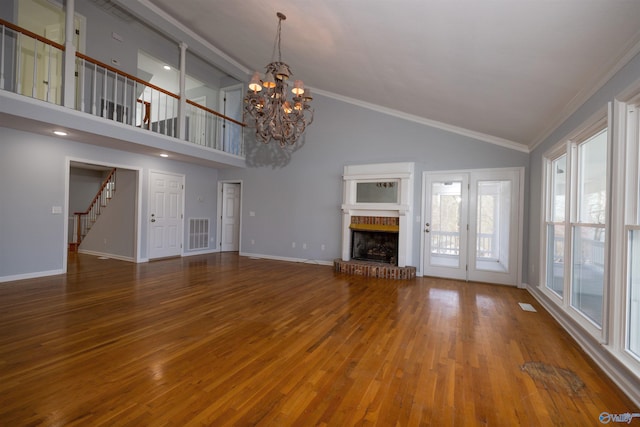 1204 Sibert Dr, Glencoe, AL 35905 - unfurnished living room with wood finished floors, a brick fireplace, a chandelier, baseboards, and stairs