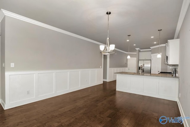 kitchen with white cabinets, hanging light fixtures, light stone counters, dark hardwood / wood-style flooring, and stainless steel appliances