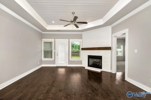 unfurnished living room featuring a fireplace, a tray ceiling, and a wealth of natural light