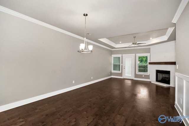 unfurnished living room featuring a tray ceiling, a fireplace, crown molding, and dark hardwood / wood-style flooring