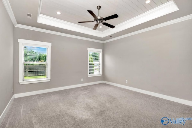 carpeted spare room with a tray ceiling, ceiling fan, and ornamental molding