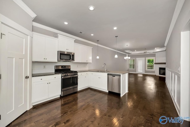 kitchen featuring sink, dark wood-type flooring, kitchen peninsula, decorative light fixtures, and appliances with stainless steel finishes