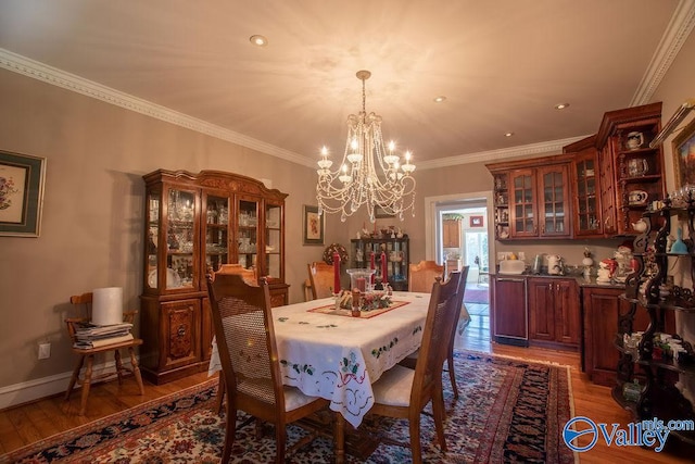 dining space with an inviting chandelier, ornamental molding, and hardwood / wood-style floors