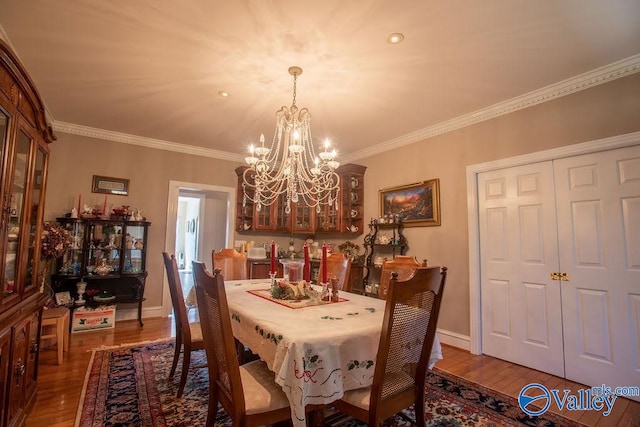 dining space featuring ornamental molding, an inviting chandelier, and hardwood / wood-style flooring