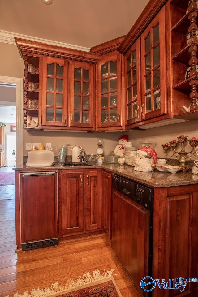 kitchen featuring crown molding, dishwasher, light wood-type flooring, and dark stone counters