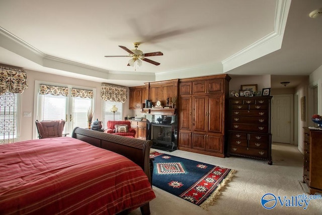 carpeted bedroom featuring ceiling fan, ornamental molding, and a tray ceiling