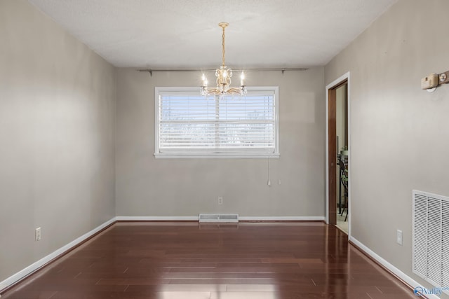 unfurnished room with dark hardwood / wood-style flooring and a chandelier