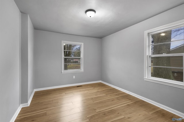 spare room with wood-type flooring and a healthy amount of sunlight