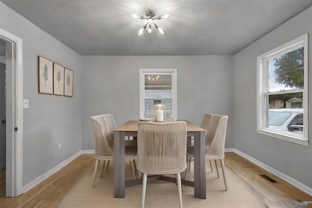 dining space featuring light hardwood / wood-style floors, plenty of natural light, and a notable chandelier