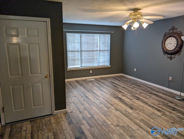 empty room featuring ceiling fan, a textured ceiling, baseboards, and wood finished floors