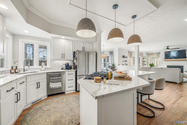 kitchen featuring light wood-style flooring, a kitchen island, appliances with stainless steel finishes, and crown molding