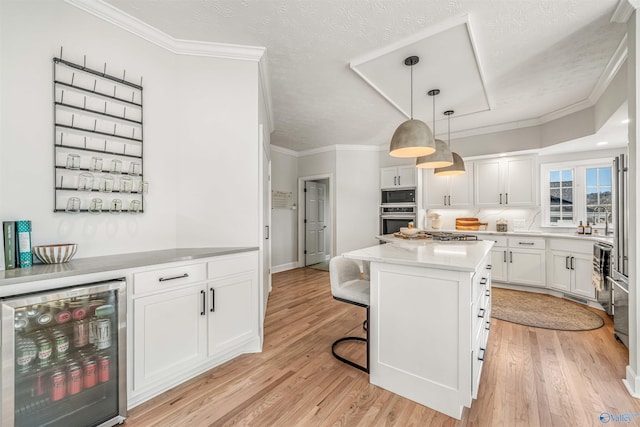 kitchen with white cabinets, light wood-style flooring, wine cooler, built in microwave, and stainless steel oven