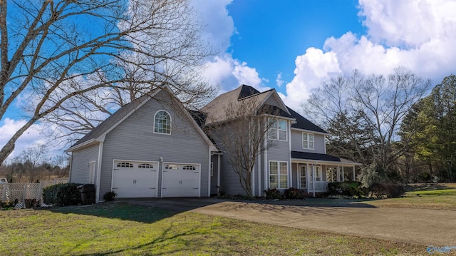 view of front of house with a garage, driveway, a front lawn, and a porch